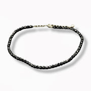 Black beaded anklet on a white background