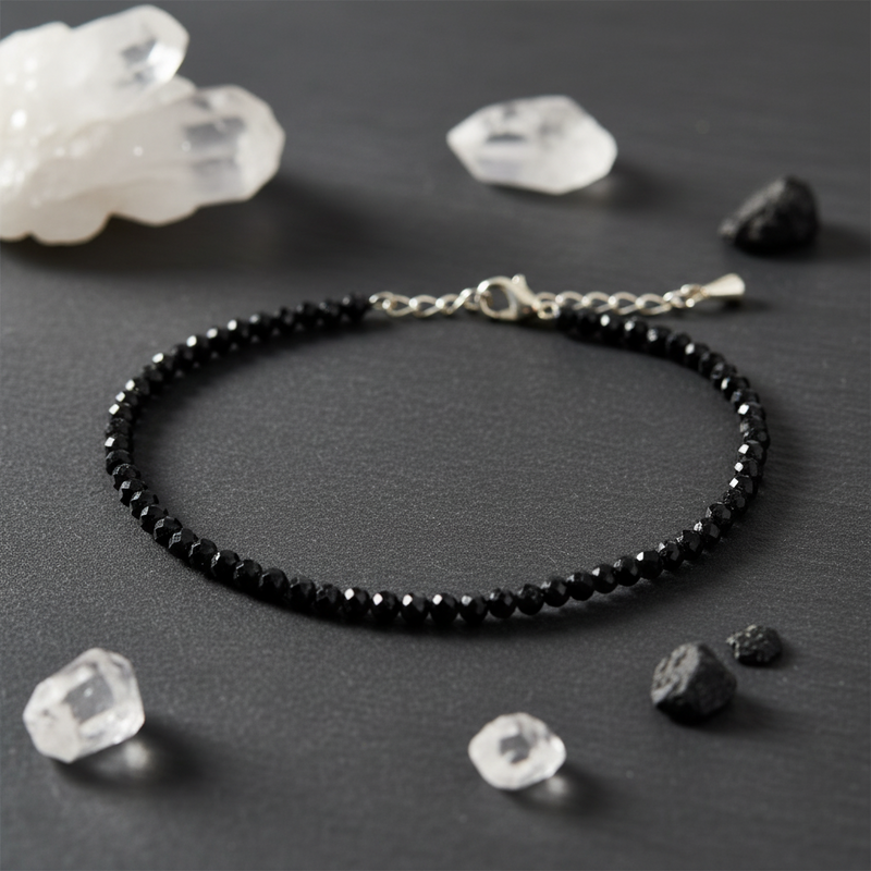 Black beaded anklet on a dark surface with crystals around