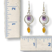 Pair of earrings with gemstones next to a ruler for scale on a white background