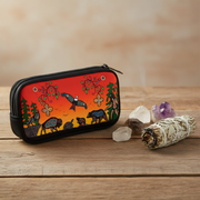 A zippered pouch with a colorful Native American-inspired print featuring buffalo, a bird, and trees on an orange-red background, displayed on a wooden surface with crystals and a sage smudge.