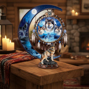 Decorative piece with wolves and a dreamcatcher design on a crescent moon shape on a wooden table in a cozy room