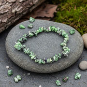 Green stone bracelet on a gray stone with natural background