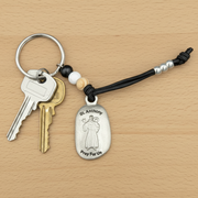 Keychain with a St. Anthony charm on a wooden surface