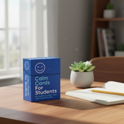 Box of 'Calm Cards For Students' on a desk with a notebook and pencil, in a bright room.