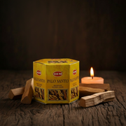 HEM Palo Santo packaging with incense sticks and a candle on a wooden surface