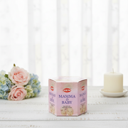 HEM Mamma & Baby product packaging on a white surface with flowers and a candle in the background