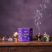 HEM Optium incense box with smoking incense stick on a wooden surface with purple background