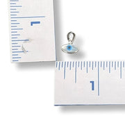 Silver eye-shaped pendant on a ruler for scale