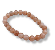 Beaded bracelet with round peach-colored beads on a white background